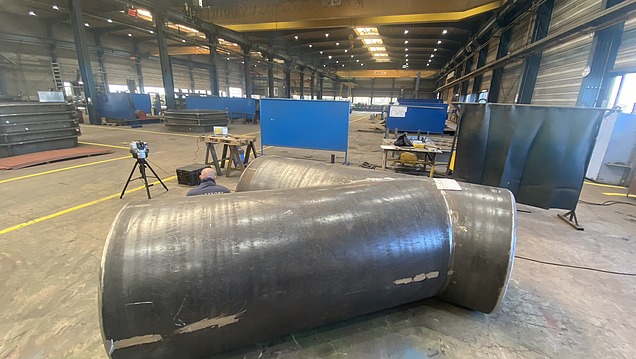 Bild in einer Fertigungshalle. Im Vordergrund befindet sich ein Hilgefort-Behälter, der mittels 3D-Verfahren und -Equipment  vermessen wird. 