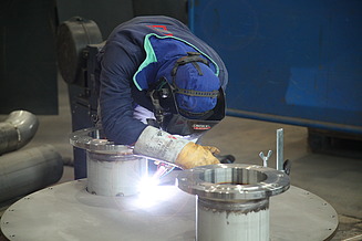 Foto eines Schweißers, der vornübergebeugt an einem Hilgefort-Behälter arbeitet