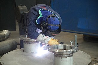 Foto eines Schweißers, der vornübergebeugt an einem Hilgefort-Behälter arbeitet