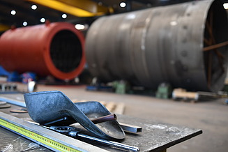 Fertigung Hilgefort, unscharfe Großbehälter im Hintergrund, Fertigungsequipment wie Schweißmasken im Vordergrund