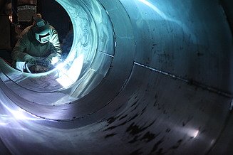 Ein Schweißer arbeitet an der Innenseite eines Behälters